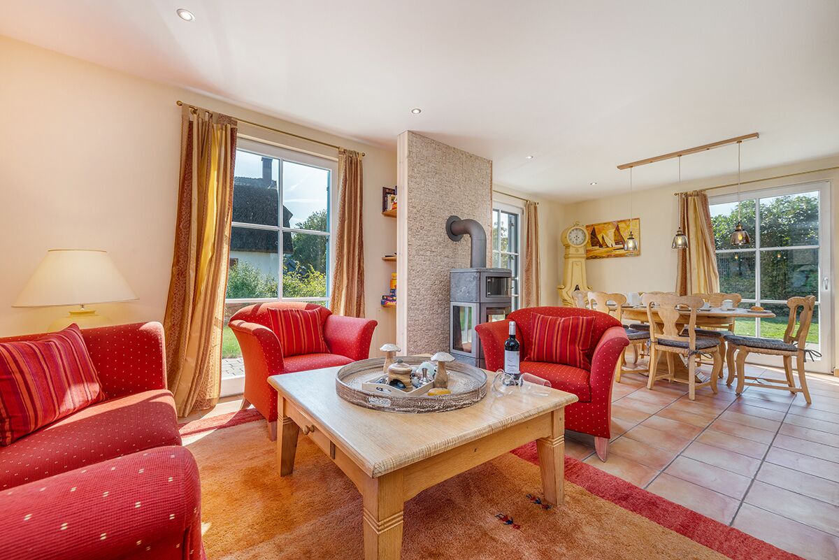 A living room with two red sofas, a coffee table, a fireplace, and a dining area with wooden furniture.