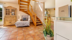 Un vaste espace de vie agrémenté d’un escalier en bois, d’un canapé, d’une armoire et d’une plante en pot.
