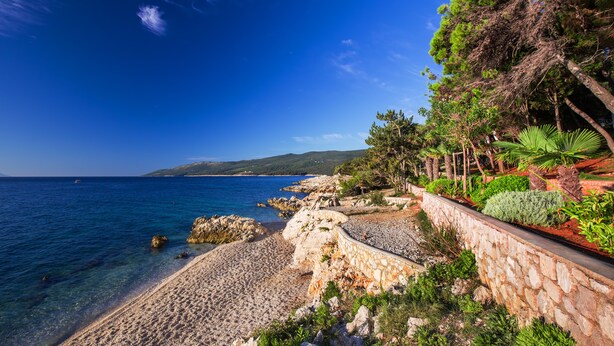 A coastal landscape with a pebble beach, a stone wall, and a clear blue sky. - Villa Primela with breathtaking sea views and private pool (Labin)