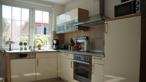 Uma cozinha moderna com lava-louças, forno e micro-ondas. Há armários, uma pia e uma janela com vista para o exterior.
