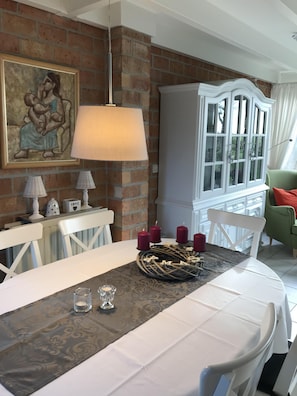 A dining area with a brick wall, a white cabinet, and a table set for six.