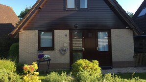 A two-story house with a dark brown roof, a stone facade, and a front door with a wreath. - Detached holiday home in picturesque Noordholland, close to the beach (Sint Maartensvlotbrug)