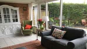 A living room with a sofa, armchair, ottoman, and a patterned rug. - Detached holiday home in picturesque Noordholland, close to the beach (Sint Maartensvlotbrug)