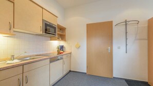 Una cocina compacta con armarios de madera, un microondas y un lavamanos.