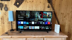 Un meuble de rangement en bois, doté d’un téléviseur à écran plat diffusant divers services de streaming, d’une lampe et d’objets décoratifs.