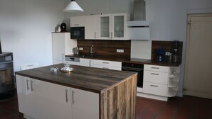 Une cuisine moderne avec des meubles blancs, un îlot central en bois et un four encastré.