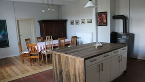 Une cuisine dotée d’un îlot central en bois, de meubles blancs et d’un coin repas avec des chaises et une table en bois.
