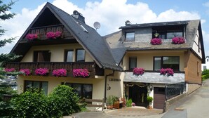 A two-story building with flower boxes on the balconies and a sign that reads "LARCHENHAUS."