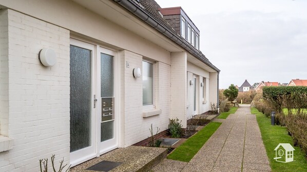 A white two-story house with a paved pathway leading to the entrance.