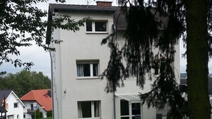 Ein mehrstöckiges Gebäude mit flachem Dach, großen Fenstern und einer überdachten Außenbereich-Sitzgelegenheit.