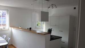 A compact kitchen with a wooden countertop, white cabinets, and a hanging light fixture. - Apartment on Bardili mountain (Bad Urach)