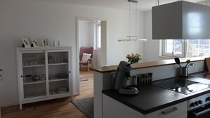 A modern kitchen with a built-in stove, a coffee maker, and a cabinet with glass doors. - Apartment on Bardili mountain (Bad Urach)