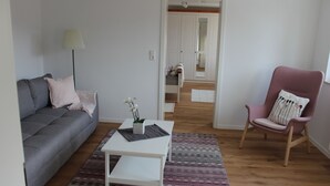 A living room with a grey sofa, a white coffee table, a pink armchair, and a patterned rug. - Apartment on Bardili mountain (Bad Urach)