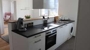 A modern kitchen with a built-in oven, microwave, and sink. There is a window providing natural light and a view of the outdoors. - Apartment on Bardili mountain (Bad Urach)