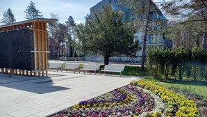 Una plaza pública con bancos, una estructura de madera y un jardín de flores.