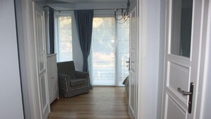 Un pasillo con una silla a cuadros, puertas blancas y una vista a través de una ventana.