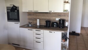 A compact kitchen with white cabinets, a built-in microwave, a sink, and a coffee maker. - Pure nature - attractive apartment on Cape Arkona, the northernmost point of Rügen (Putgarten)