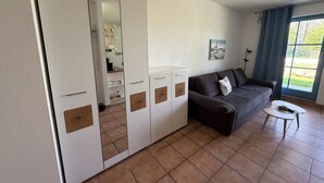 A modern living room with a sofa, a small table, and a large wardrobe with mirrored doors. - Pure nature - attractive apartment on Cape Arkona, the northernmost point of Rügen (Putgarten)