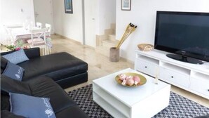 Ein modernes Wohnzimmer mit einem schwarzen Sofa, einem weißen Couchtisch und einem Flachbildfernseher.