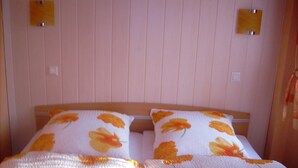 Ein Bett mit blumigem Bettzeug und zwei an der Wand befestigten Lampen.