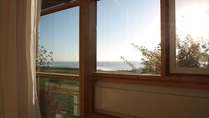 Ein Zimmer mit großen Fenstern mit Blick auf eine Küstenlandschaft.