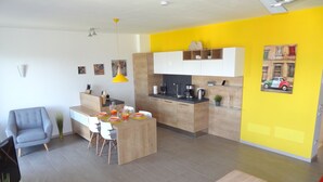 Eine moderne Küche mit Holzschränken, eine Essecke mit Tisch für vier Personen und eine leuchtend gelbe Akzentwand.