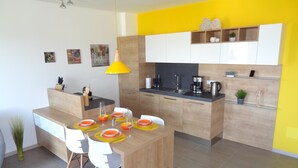 Eine moderne Küche mit Holzschränken, einer zentralen Kochinsel mit Sitzgelegenheiten und einer leuchtend gelben Akzentwand.