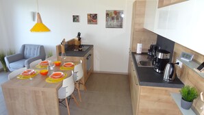 Eine moderne Küche mit Essbereich, ausgestattet mit einer Holzinsel, einem grauen Sofa und einer gelben Pendelleuchte.