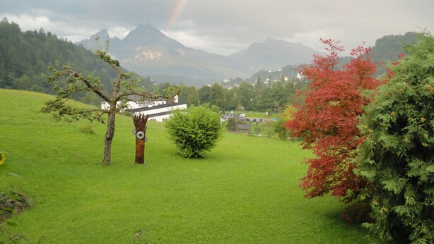 A lush green landscape with a rainbow, a white building, and mountains in the background. - 80 sqm apartment, 2 bedrooms to 5 pers., 2 balconies, sunny & quiet (Berchtesgaden)