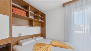 A hotel room with a bed, a wooden headboard, a built-in shelf unit, and a large window with sheer curtains. - Apartment in Sukošan with Seaview, Terrace, Air condition, WIFI (3495-1) (Sukošan)