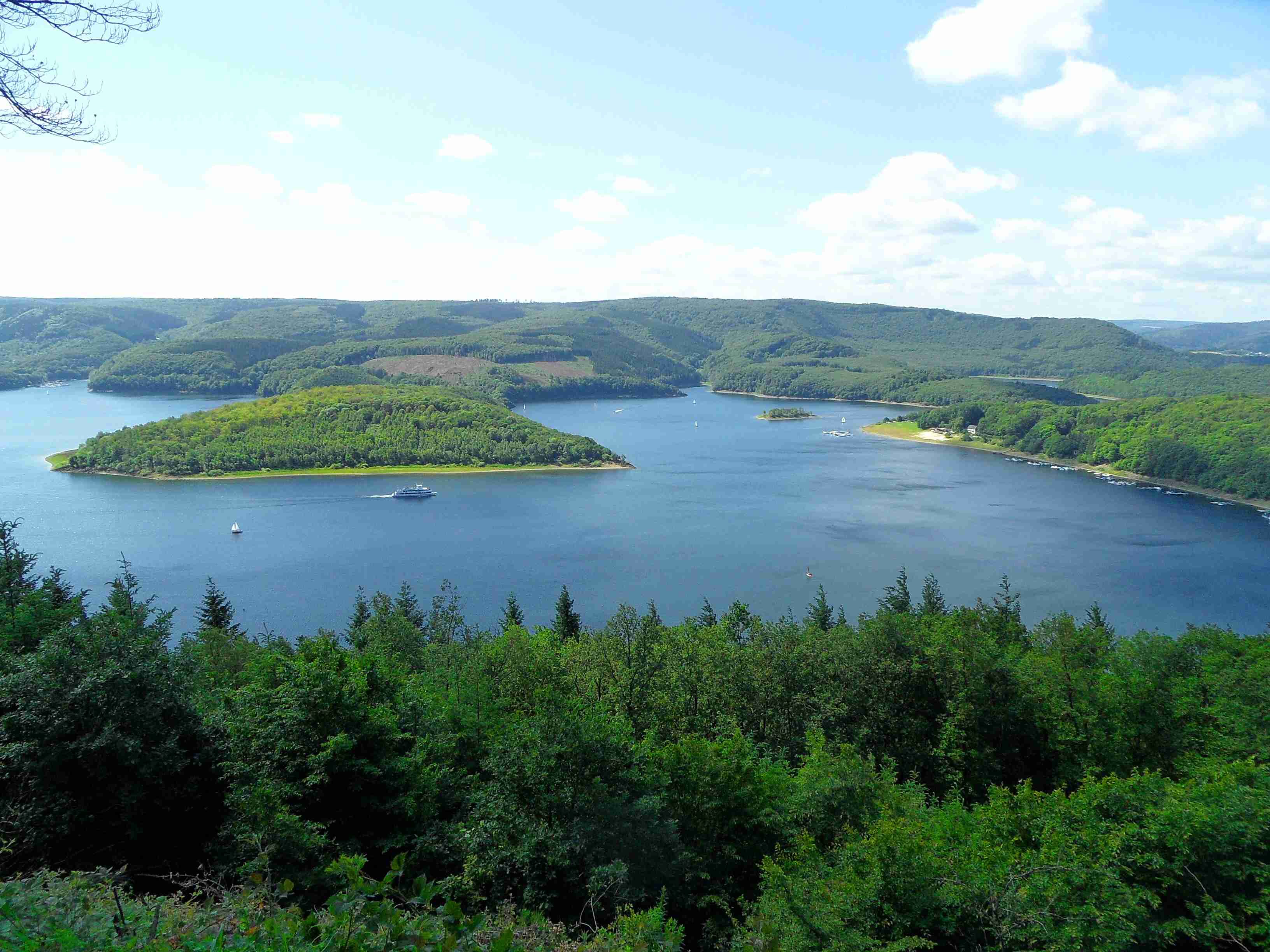 A large body of water surrounded by forested hills.