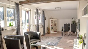 Ein modernes Wohnzimmer mit einem Glastisch, Ledersofas und einem weißen Bücherregal.