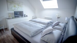 Ein Schlafzimmer mit einem Bett, einem Schreibtisch, einem Sessel, einem Fernseher und einem Fenster.