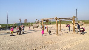 A sandy playground with wooden structures and tire swings.