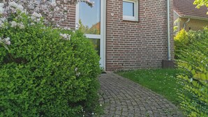 A brick house with a number 837 on the door, a small window, and a brick pathway leading to the entrance.