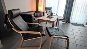 A modern living room with a sofa, two armchairs, a coffee table, and a small side table.