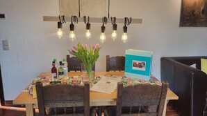 A dining table with a floral tablecloth, a vase of tulips, and a blue folder with a photo. - Apartment Berg & Barkenhoff vis-à-vis the Barkenhoff for 1-5 people (Worpswede)