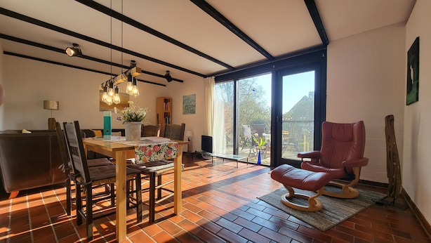 A modern living room with a dining area, large windows, and a red leather chair. - Apartment Berg & Barkenhoff vis-à-vis the Barkenhoff for 1-5 people (Worpswede)