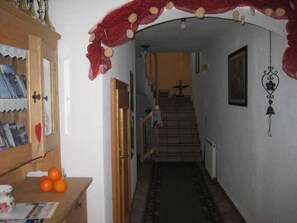 A hallway with a wooden cabinet, oranges, and a staircase leading to another room. - Mill - Blue Silvretta (Galtür)