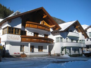 A multi-story building with balconies, a sign reading 'Mühle,' and a snow-covered ground. - Mill - Blue Silvretta (Galtür)