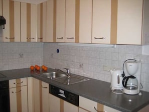 A kitchen with striped cabinets, a sink, a dishwasher, and a coffee maker. - Mill - Blue Silvretta (Galtür)