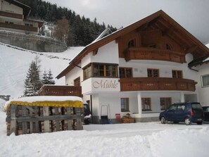 A two-story building with a sign 'Mühle' on the front, a wooden balcony, and a parked car. - Mill - Blue Silvretta (Galtür)