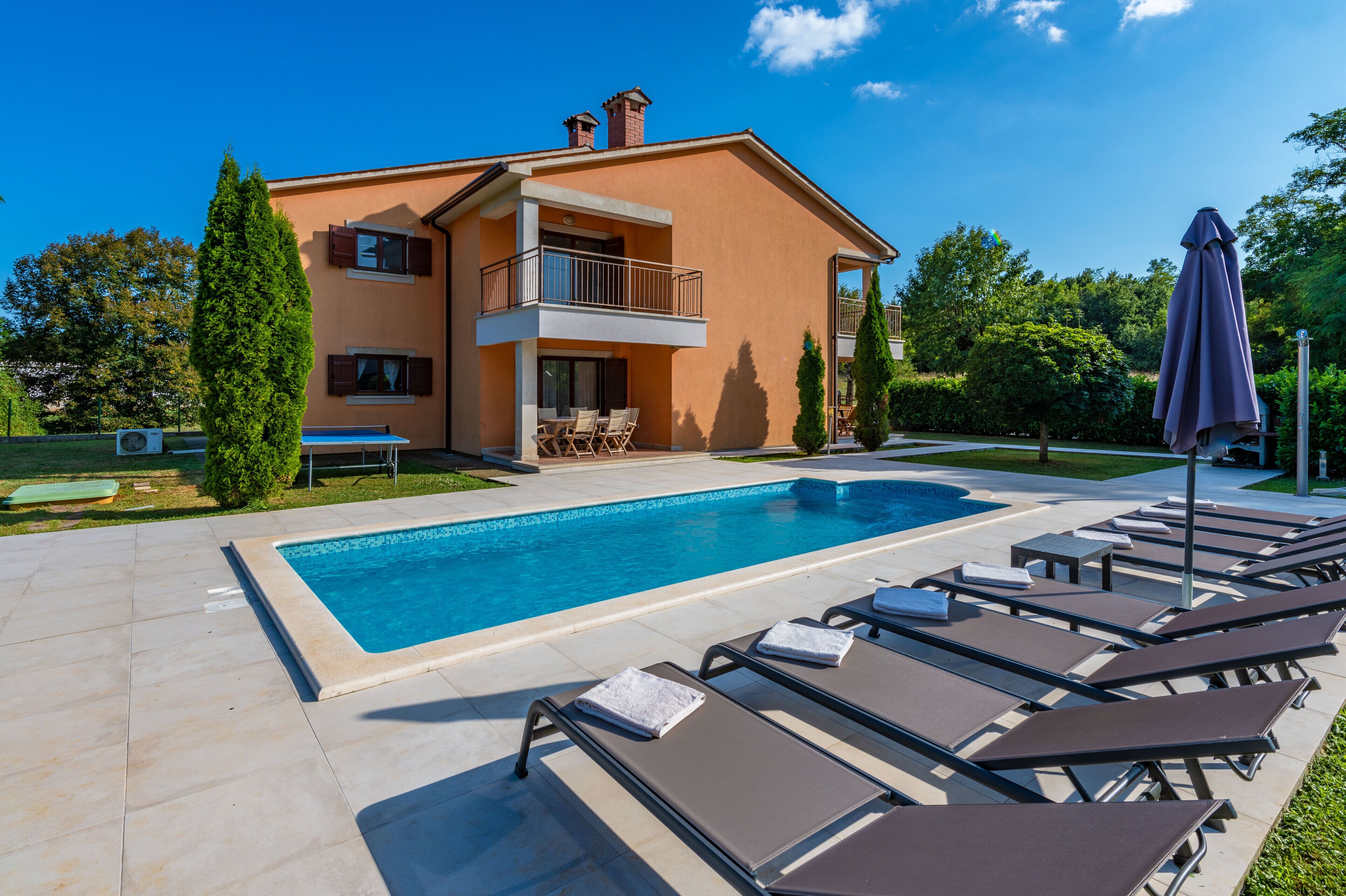 Un bâtiment à deux étages doté d’une piscine, de chaises longues et d’un patio couvert.