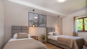 Une chambre d’hôtel avec deux lits, une plante en pot et des œuvres d’art accrochées au mur.