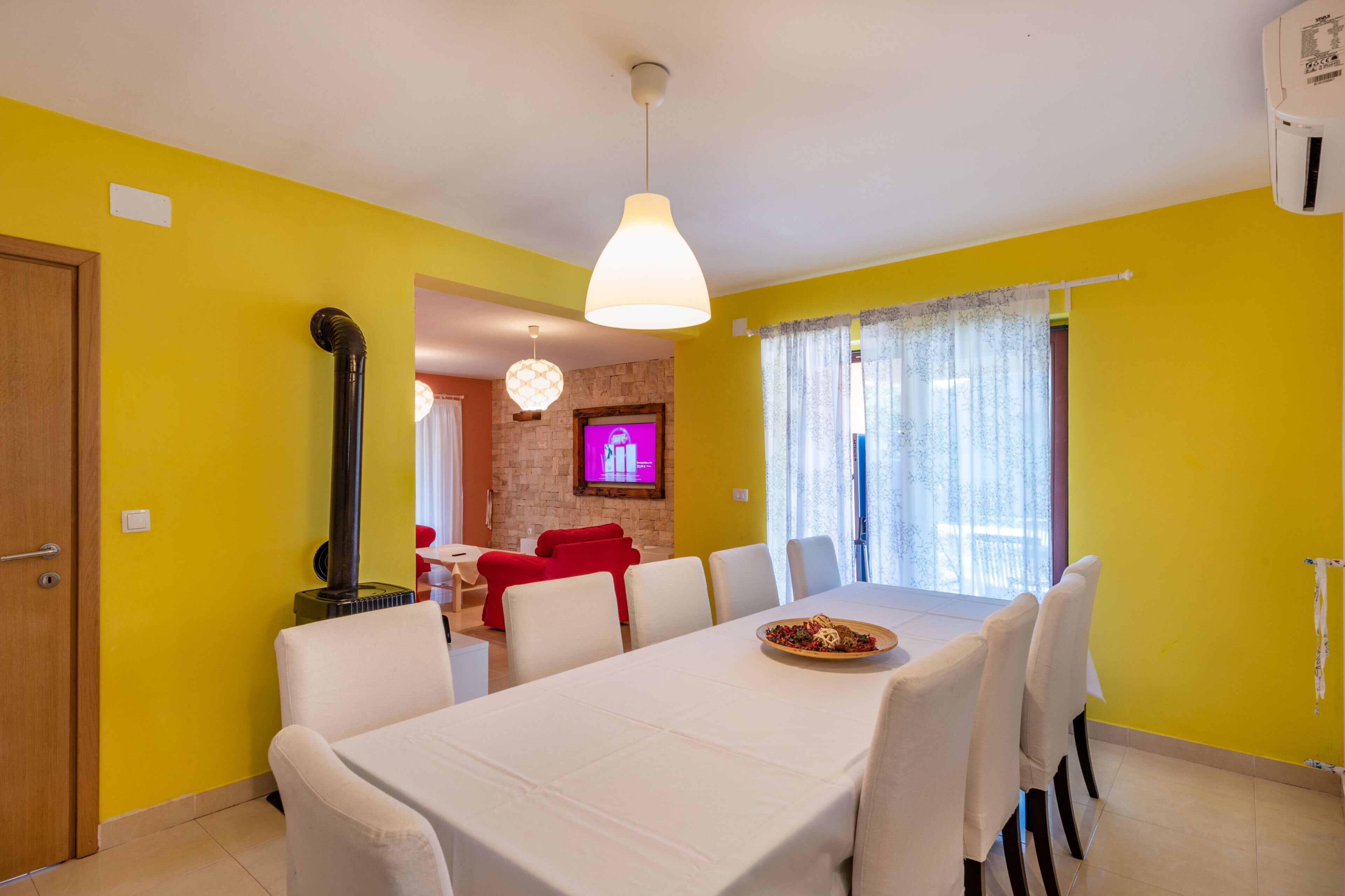 A dining area with a table set for six, a fireplace, and a television in the background.