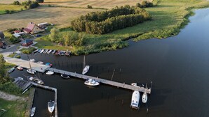 A marina with boats docked, a pier extending into a body of water, and a rural landscape with fields and trees in the background. - Comfortable, affordable, quiet, located at the harbor and surrounded by meadows, pets welcome (Pruchten)