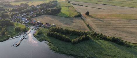 An aerial view of a riverside village with houses, a dock, and fields.