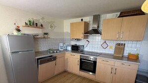 A compact kitchen with a refrigerator, microwave, oven, and sink. - Comfortable, affordable, quiet, located at the harbor and surrounded by meadows, pets welcome (Pruchten)