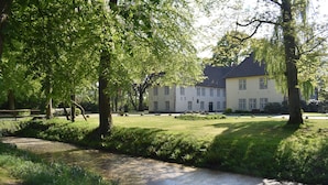 Een groot gebouw met veel ramen en een verzorgd gazon.