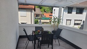 Um pátio coberto ao ar livre com uma mesa e cadeiras, uma planta em vaso e uma estátua.